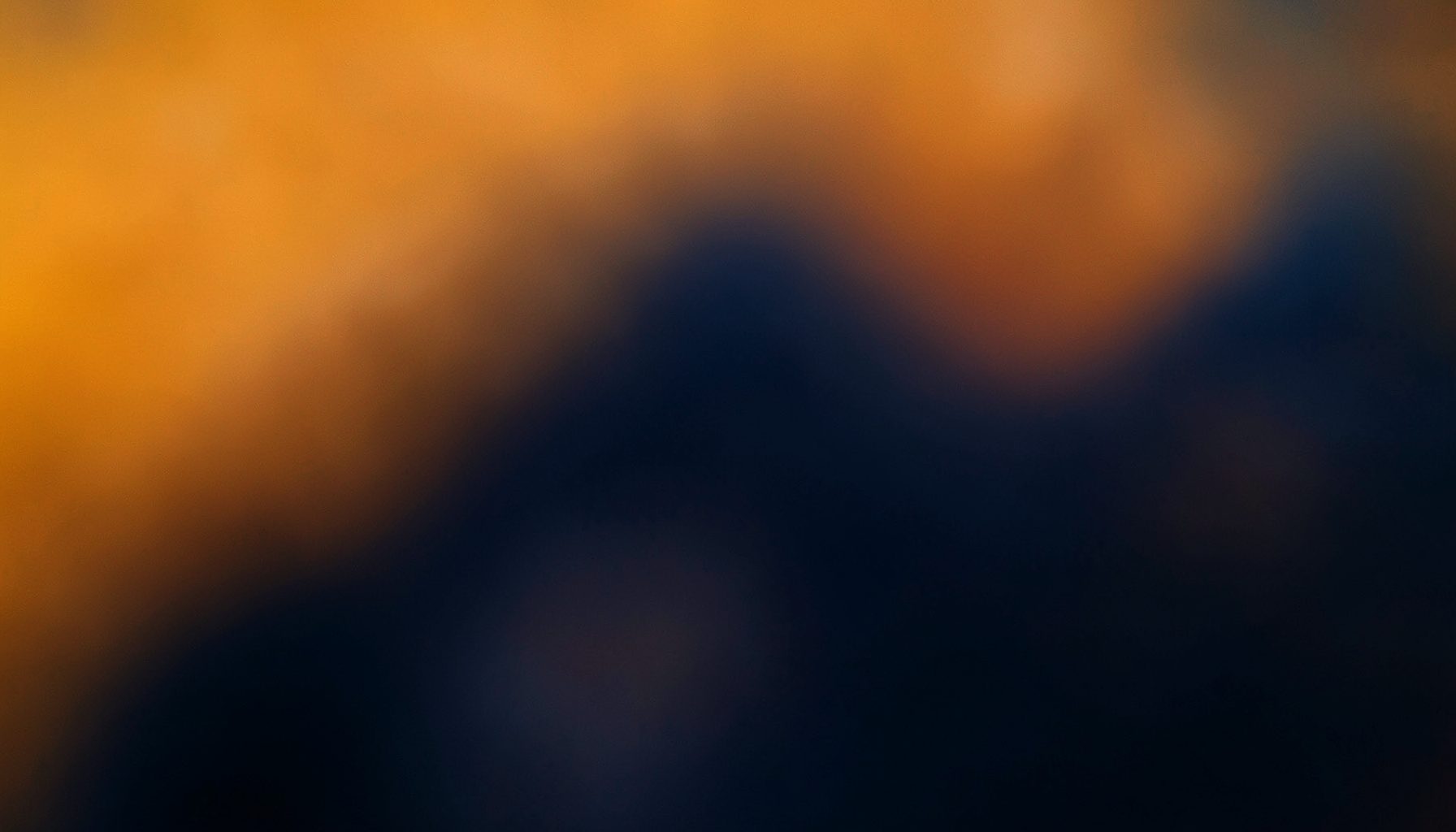 Warm amber and deep navy abstract gradient with soft lens blur, suggesting a cinematic video editing workspace